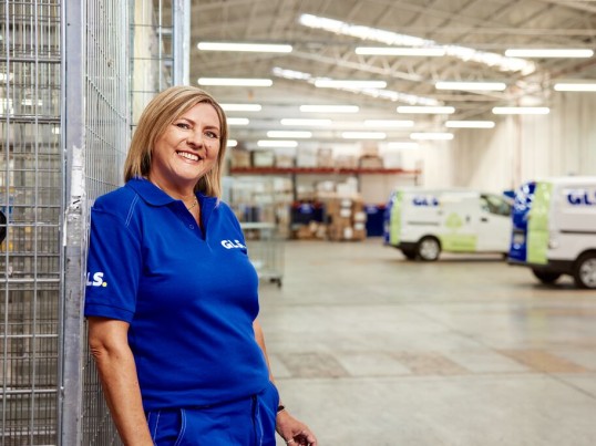 A GLS woman stands smiling in a GLS depot