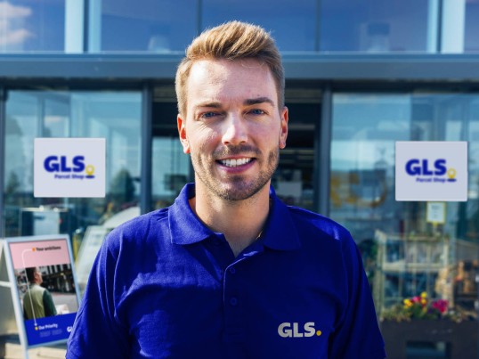 GLS delivery man standing in front of a GLS Parcel Shop