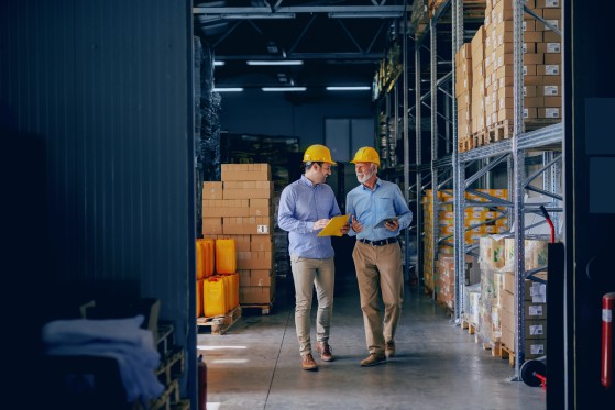 Two workers talking as they walk in a warehouse.